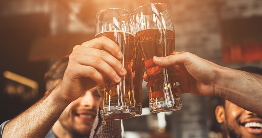 A group of men toast glasses of beer in a pub