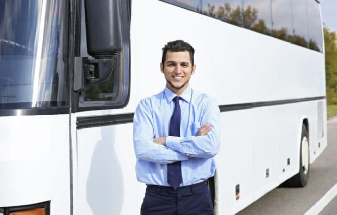 A charter bus driver in front of a bus