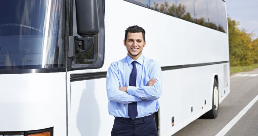 A charter bus driver in front of a bus
